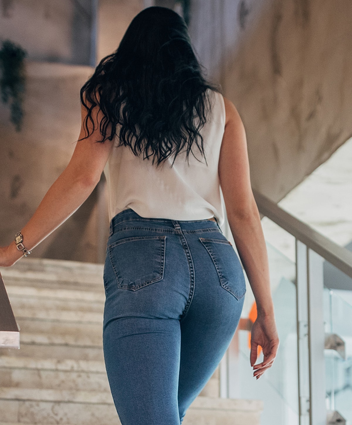 Woman walking up stairs in fitted jeans.
