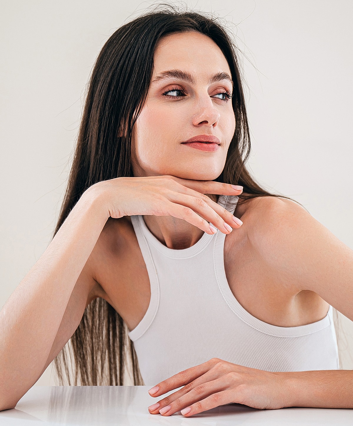 Woman with long hair resting her chin on hand