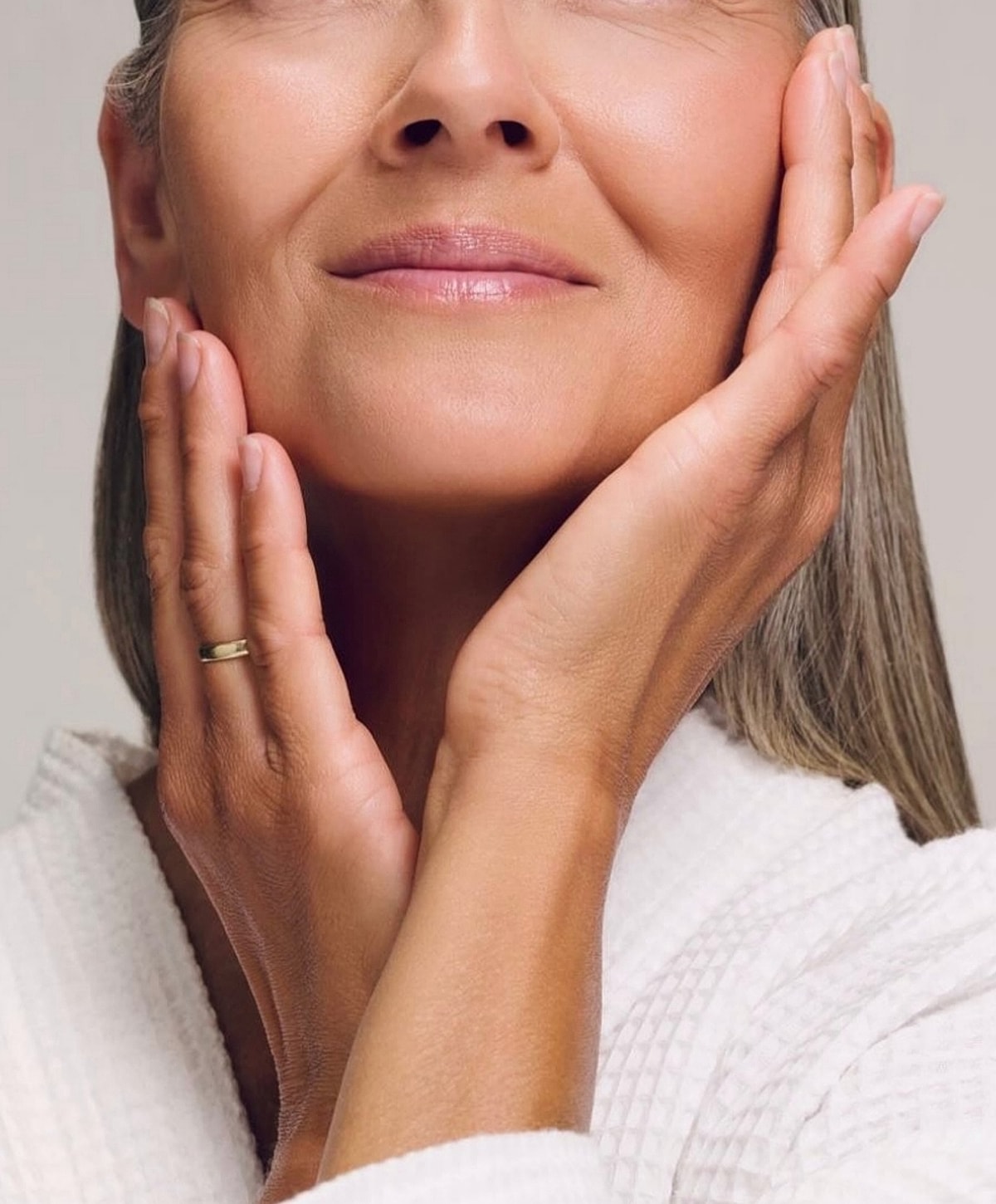 Woman gently touching her face, glowing skin.