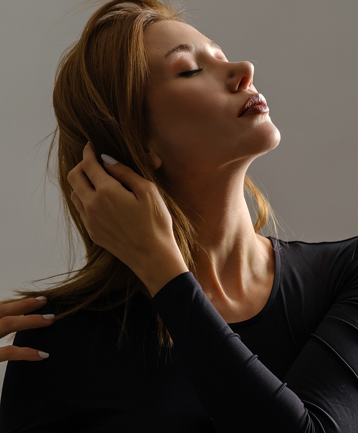Woman with closed eyes adjusting her hair.
