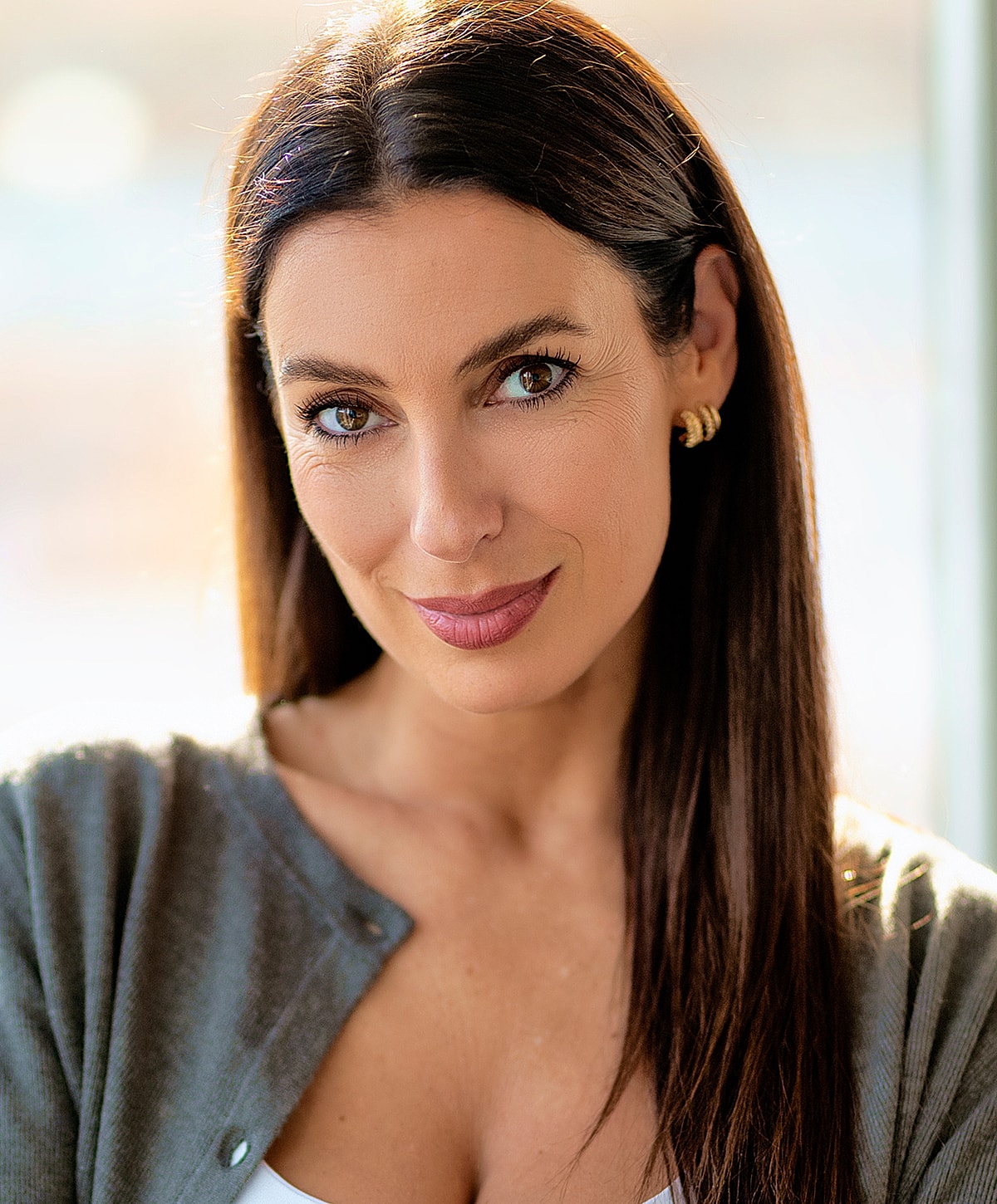 Smiling woman with long, dark hair indoors.