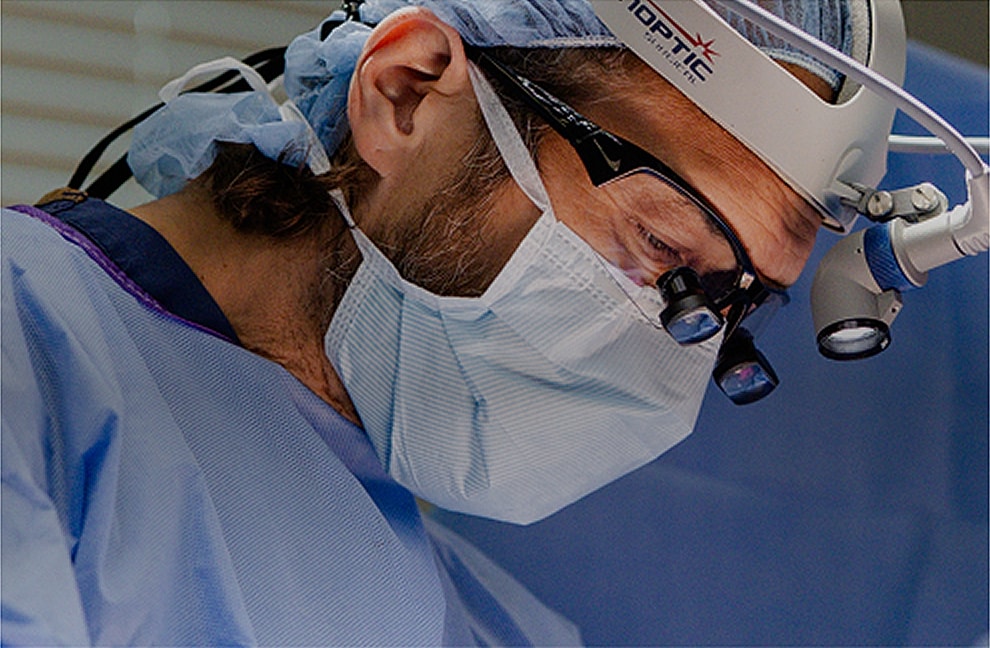 Surgeon performing a procedure in a surgical environment.