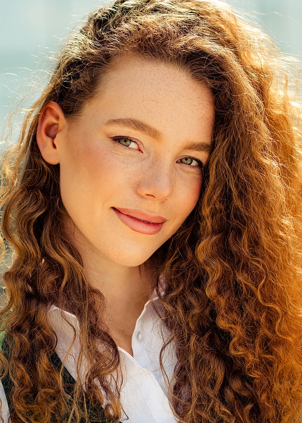 Smiling woman with curly hair and green eyes.