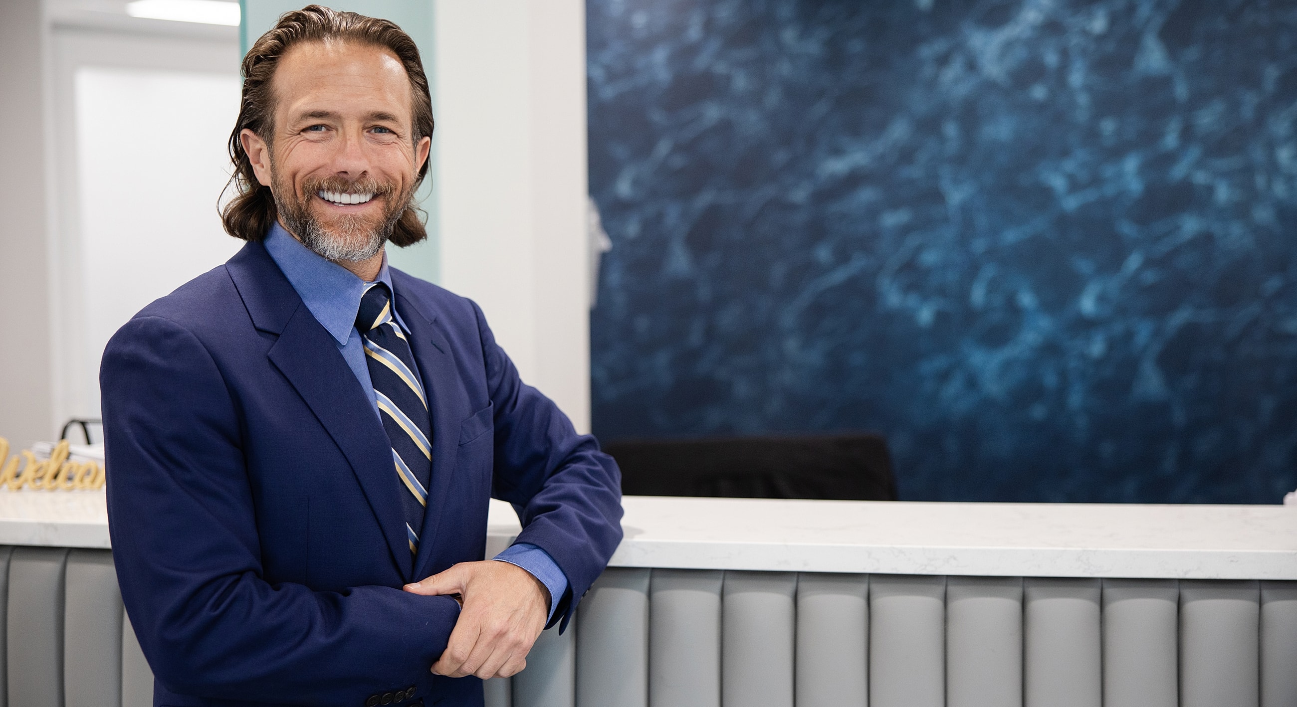 Smiling man in suit at reception desk.