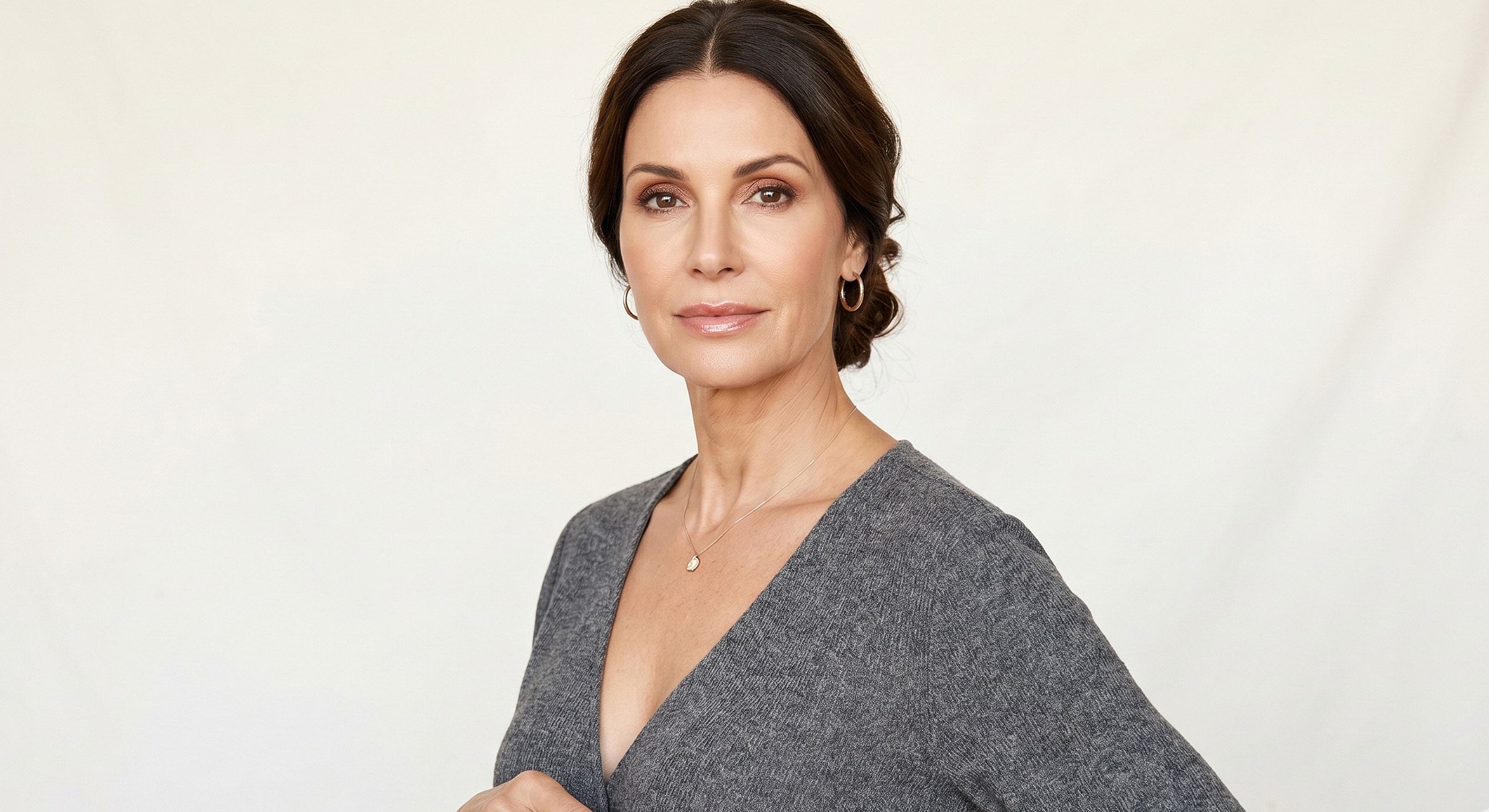 Woman posing in a gray sweater, natural lighting.