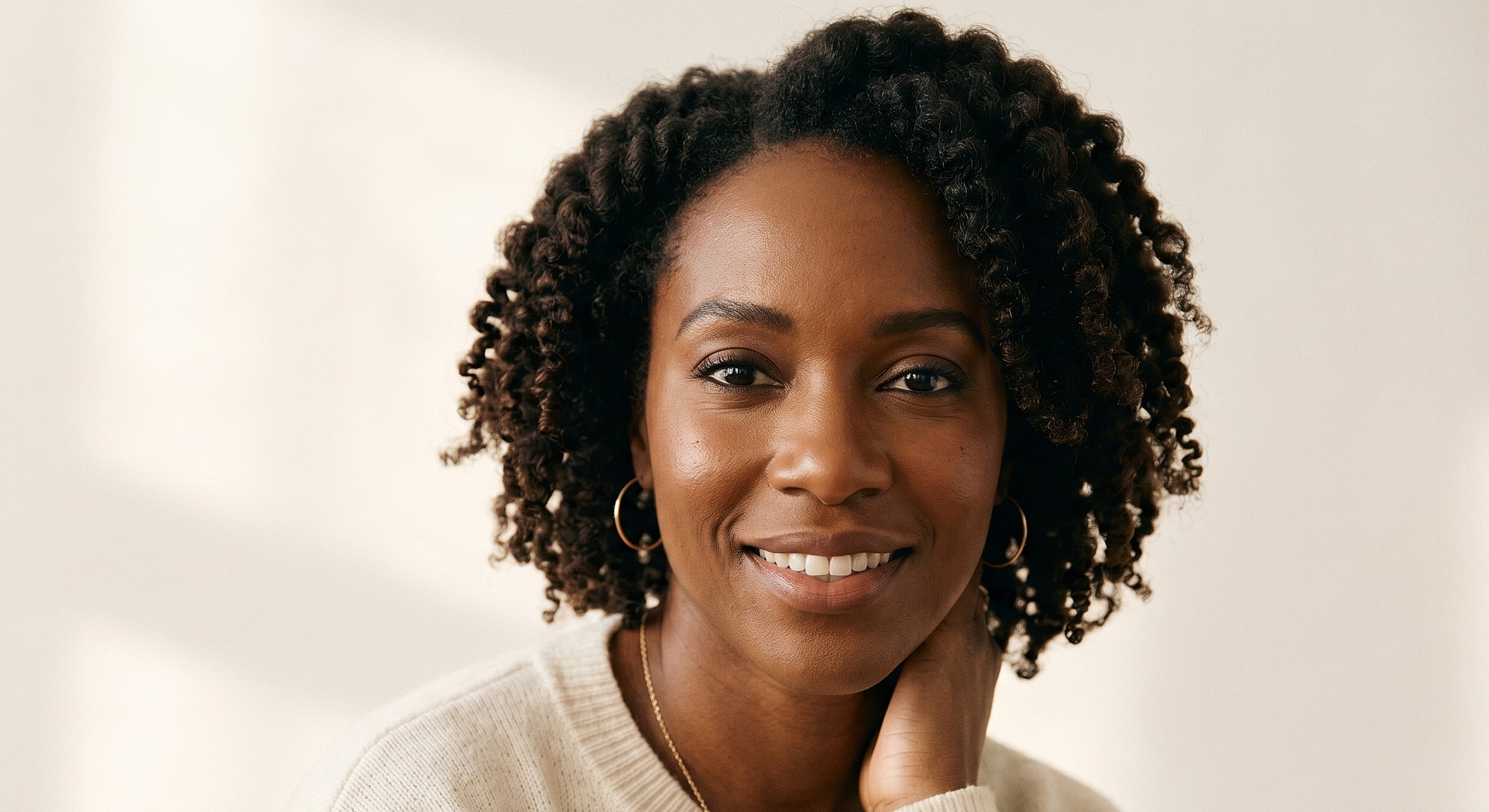 Smiling woman with curly hair in natural light.