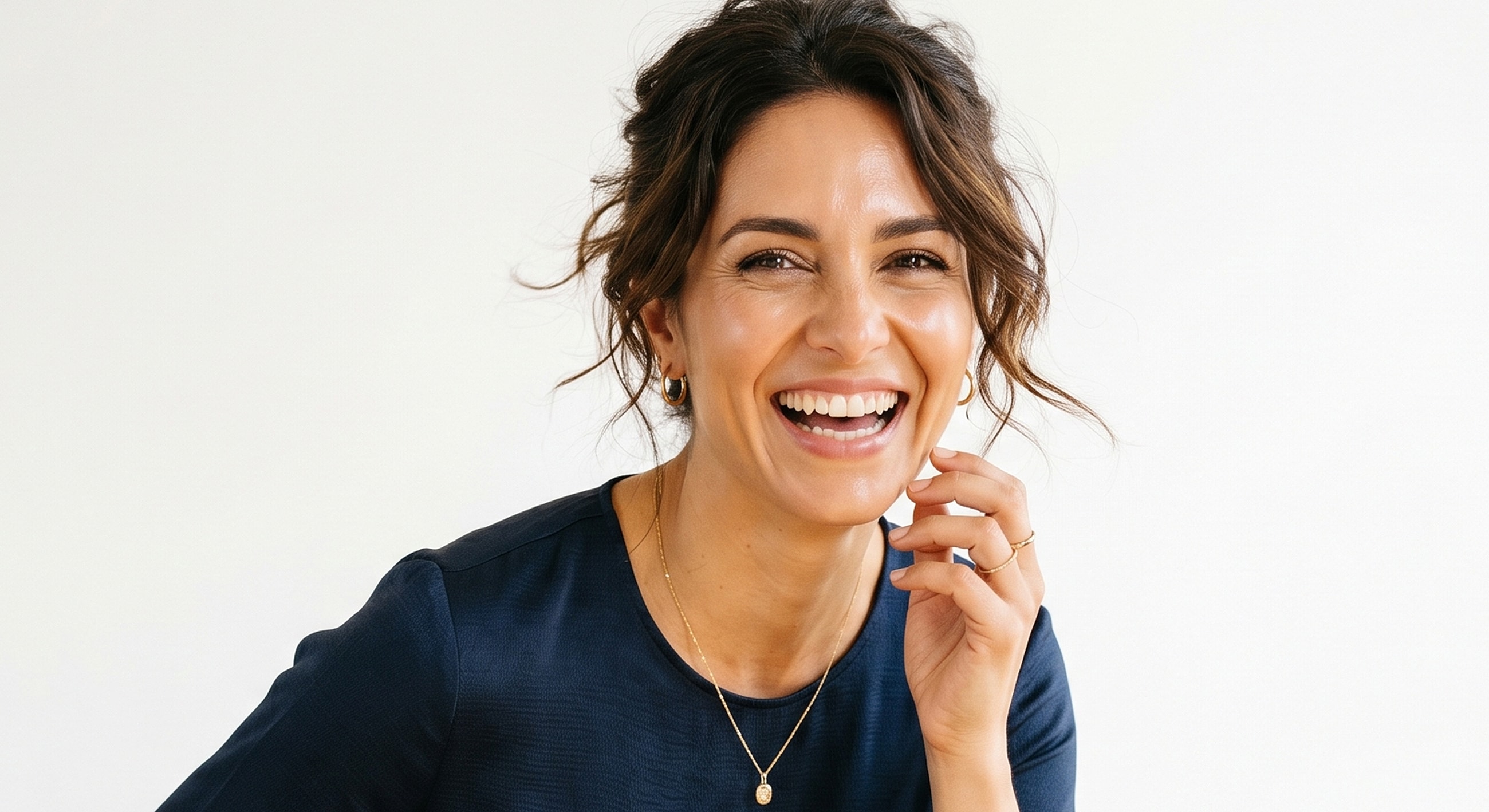 Smiling woman with curly hair and jewelry.