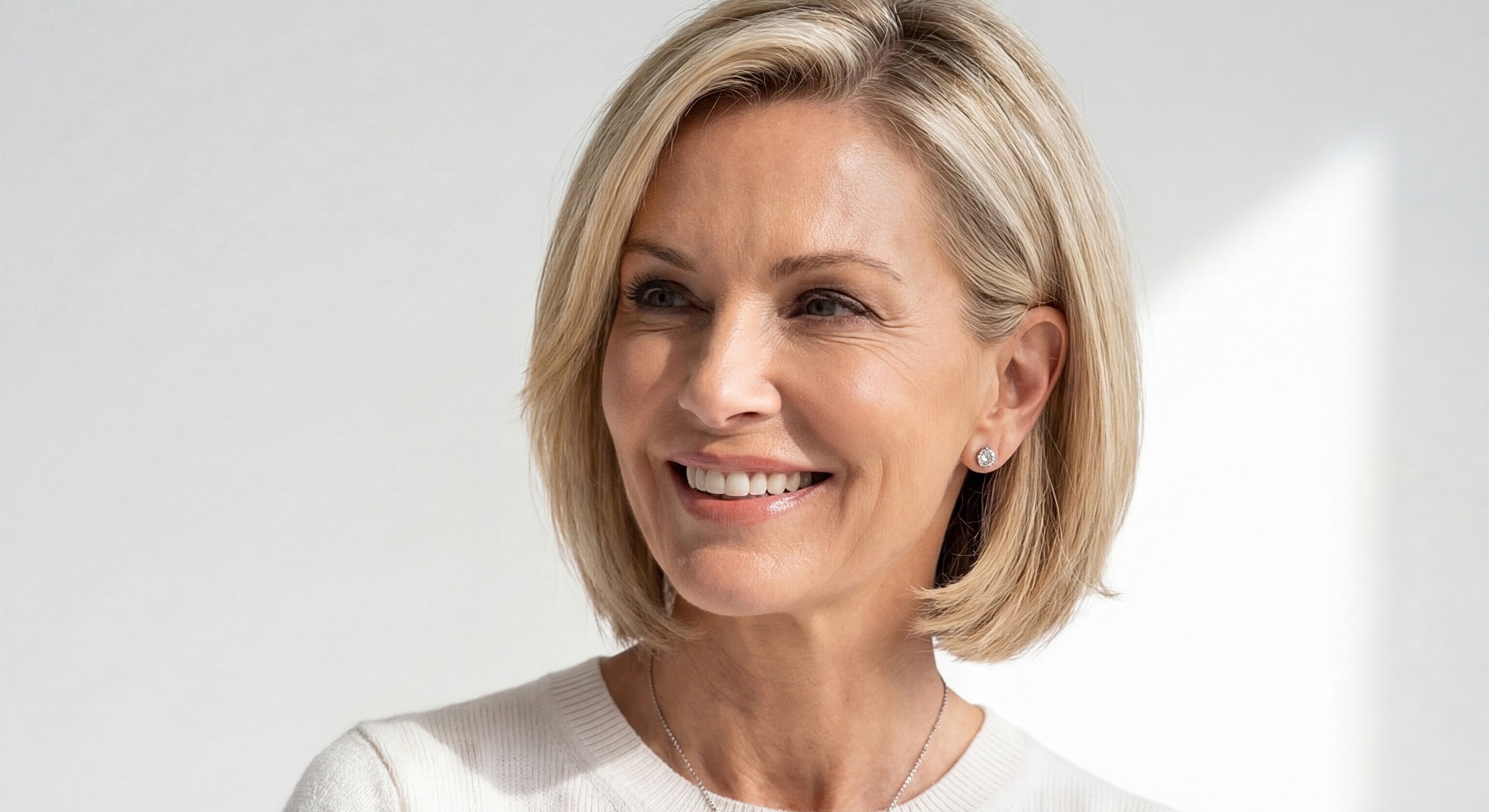 Smiling woman with blonde bob hairstyle indoors.