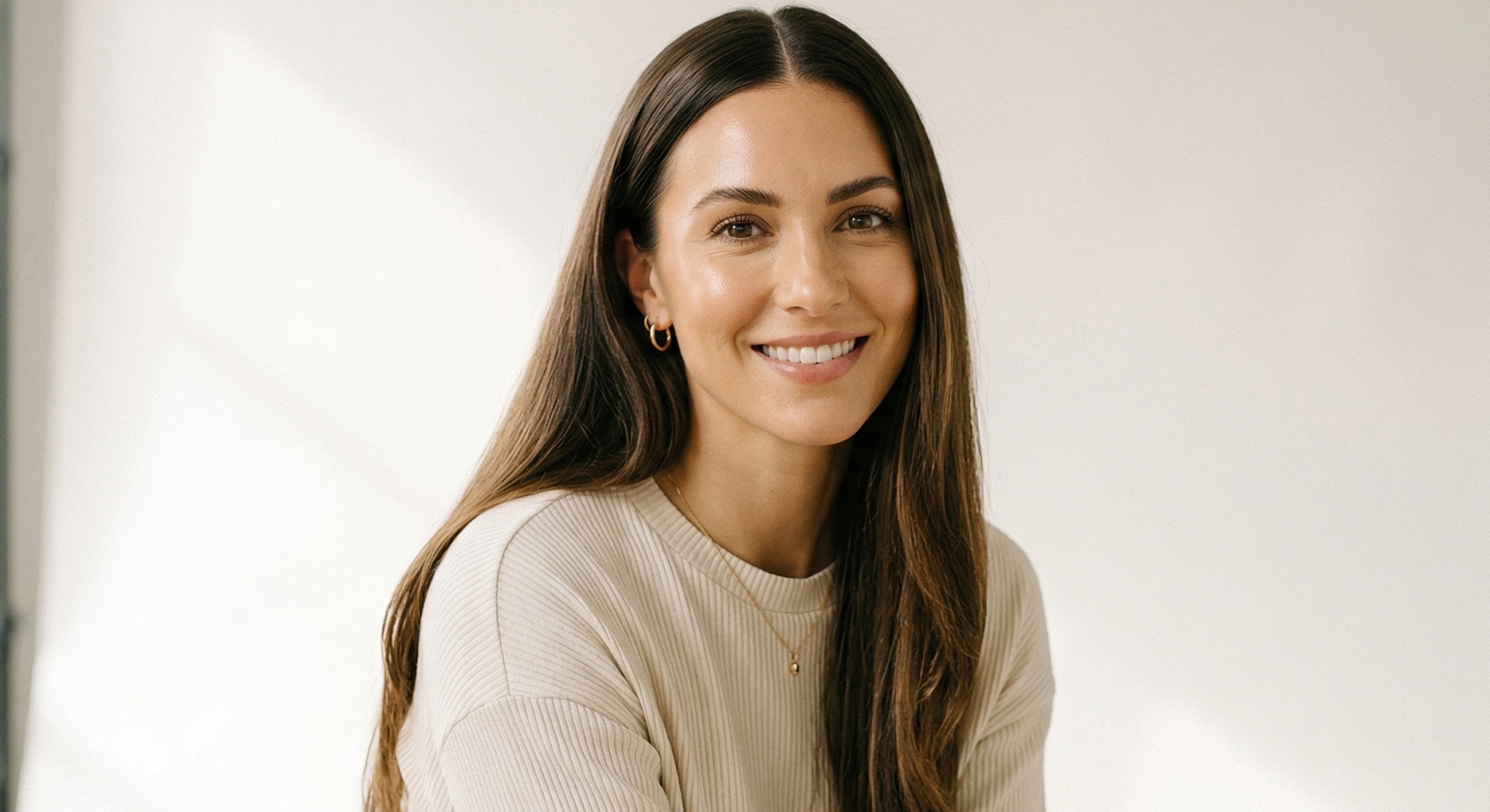 Smiling woman with long hair in neutral clothing.