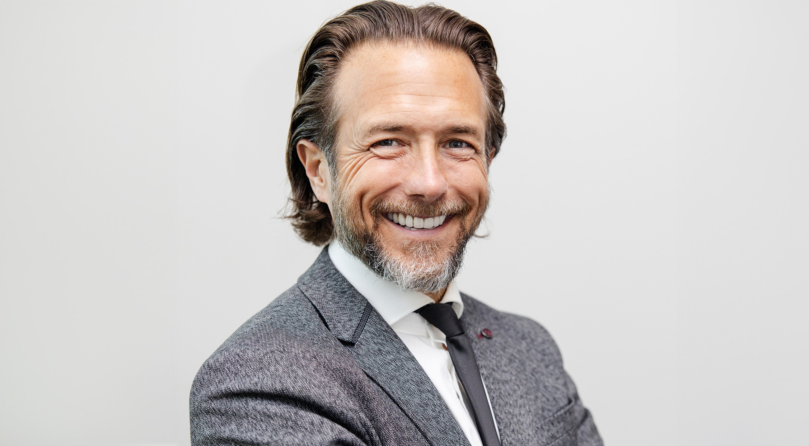 Smiling man in a suit against a neutral background.